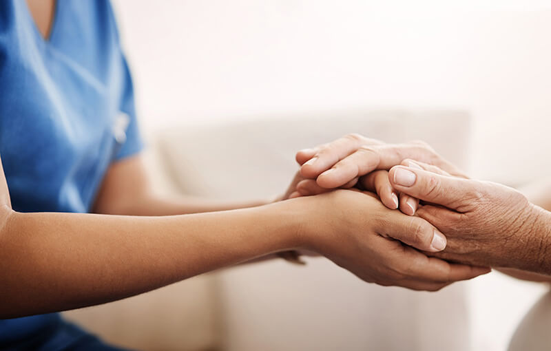 A nurse holding a patients hands